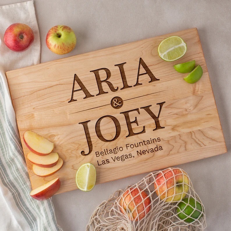 Maple wood cutting board with engraved names and address on it.