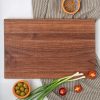 A wooden cutting board with olives and onions on it.