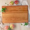 A wooden cutting board with apples and a bag of apples.