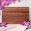 A wooden cutting board with purple lilies on it.