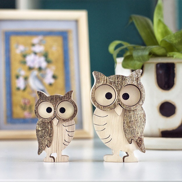 Two wooden owl figurines on a table.