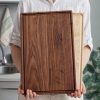 A woman holding up a wooden cutting board.