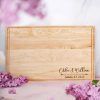 A wooden cutting board with the name of the bride and groom on it.