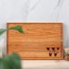 A wood cutting board with a name and a jar of nuts.