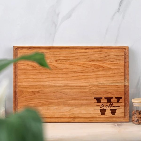 A wood cutting board with a name and a jar of nuts.