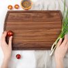 A person holding a wooden cutting board with onions on it.