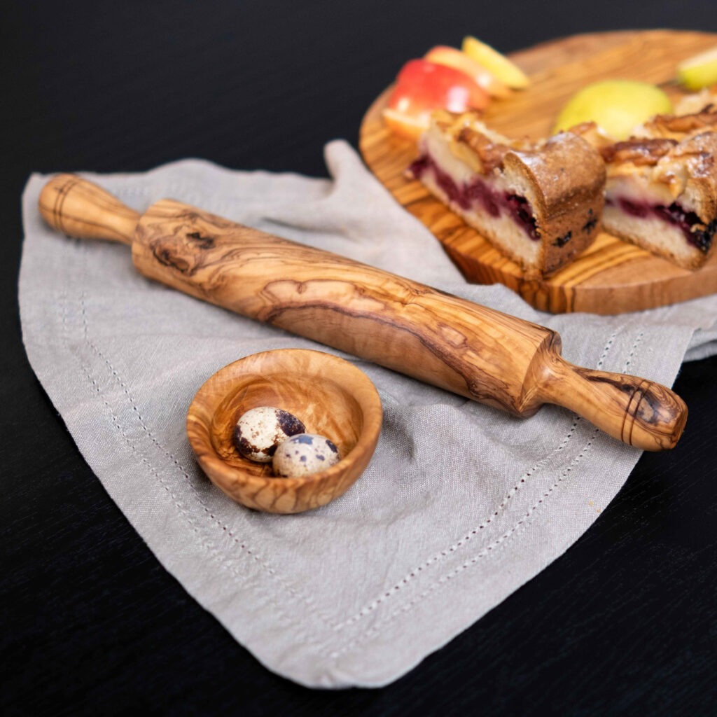 A wooden rolling pin next to a piece of cake.