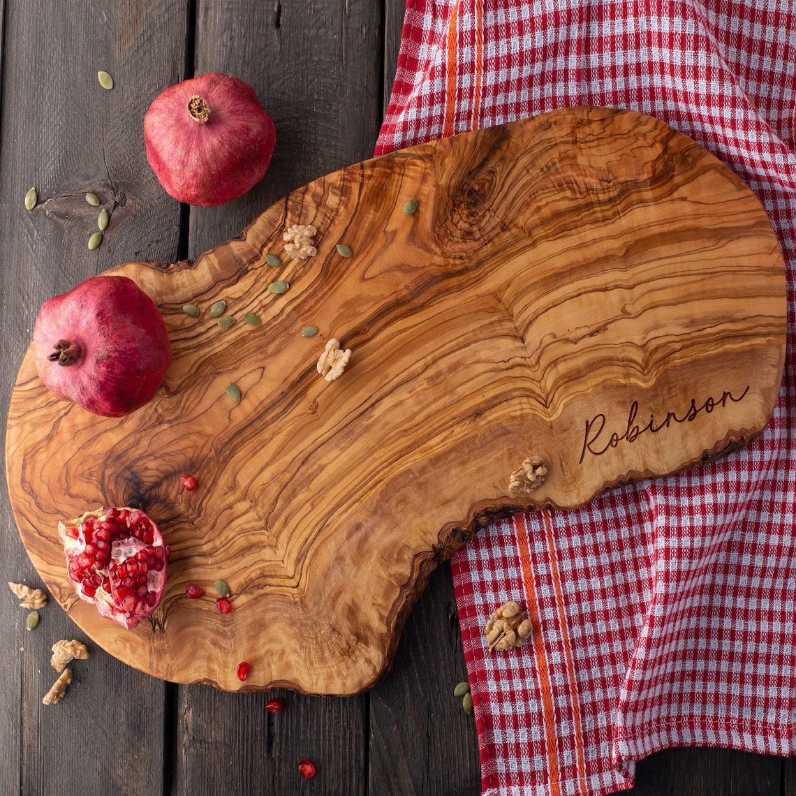 Personalized Olive Wood Live Edge Board with pomegranates and pomegranate seeds.
