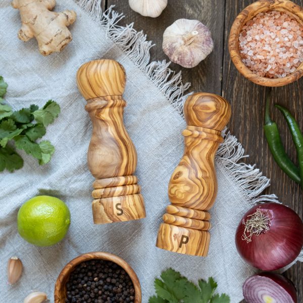 A set of wooden pepper mills and spices on a wooden table.