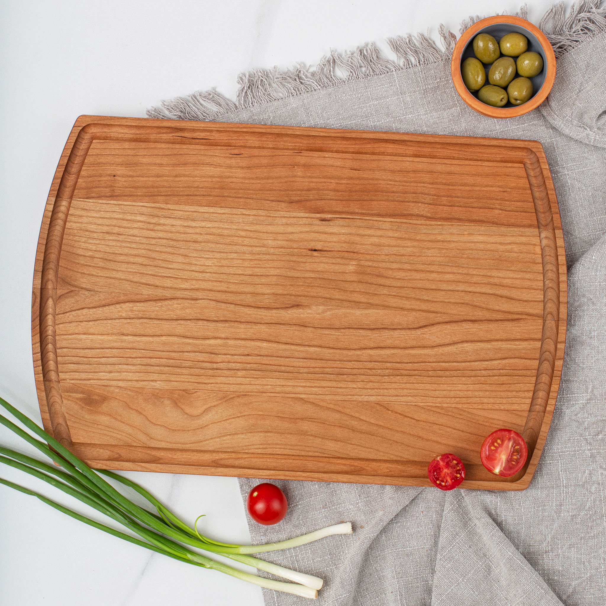 A wooden cutting board with olives and onions on it.