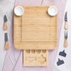 A neatly arranged cheese board with an assortment of knives and bowls on a marble background.