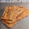 Three Live Edge Olive Wood Boards with Personalization laying on top of kitchen counter.
