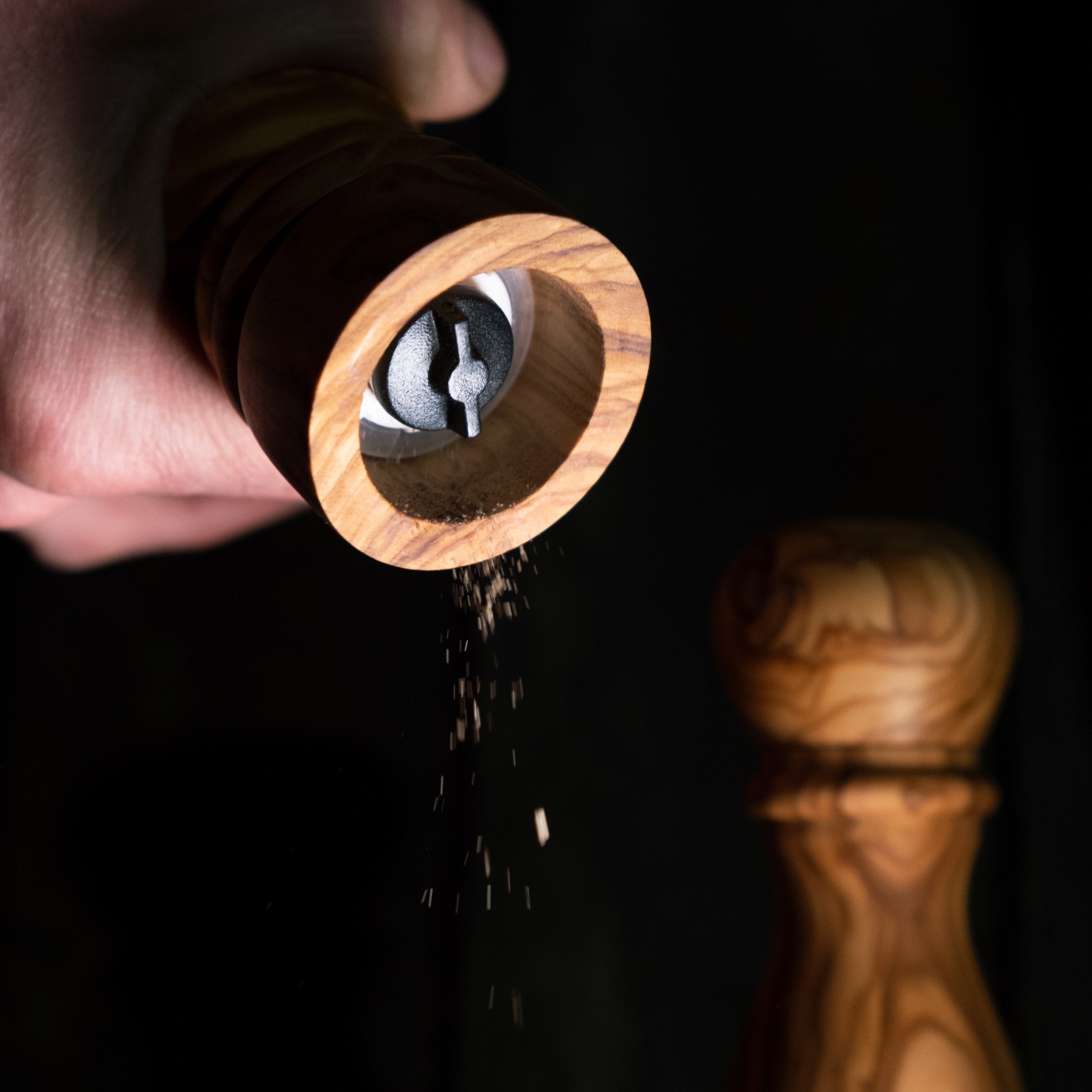 A hand holding a pepper grinder.