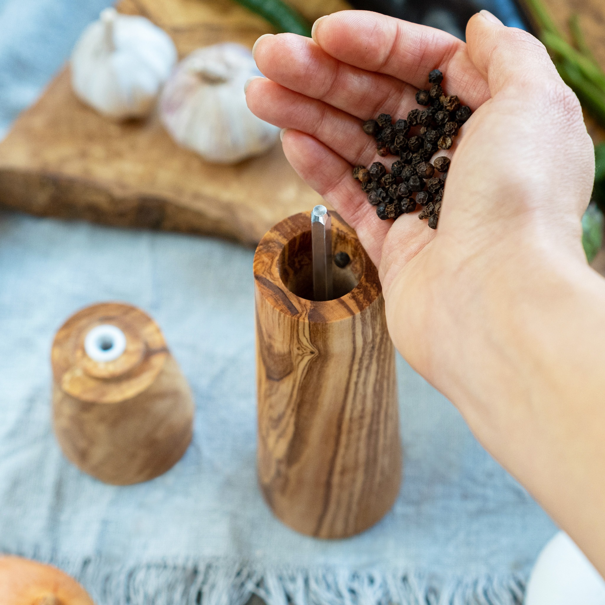 A person holding black peppercorns.
