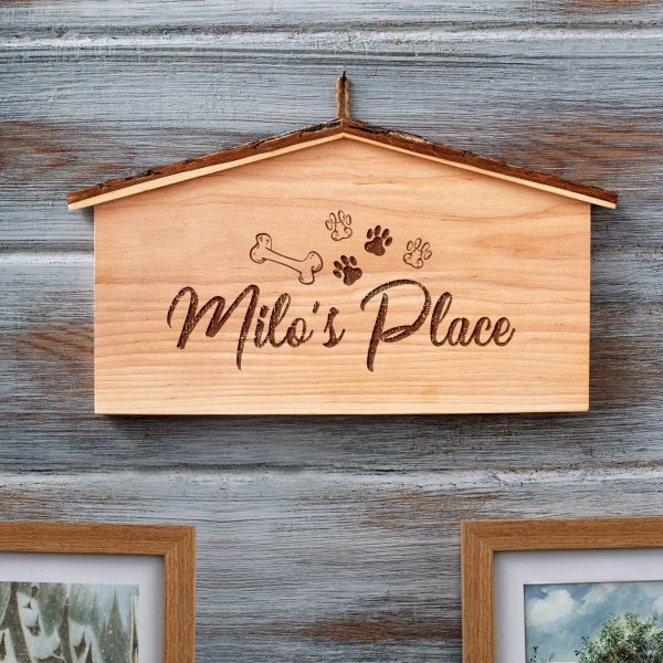 A wooden dog house with paw prints on it.