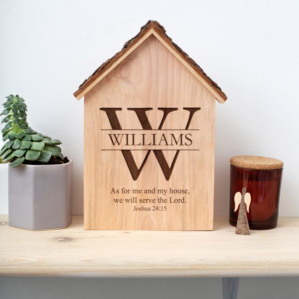 A wooden house with a candle and a plant on a shelf.