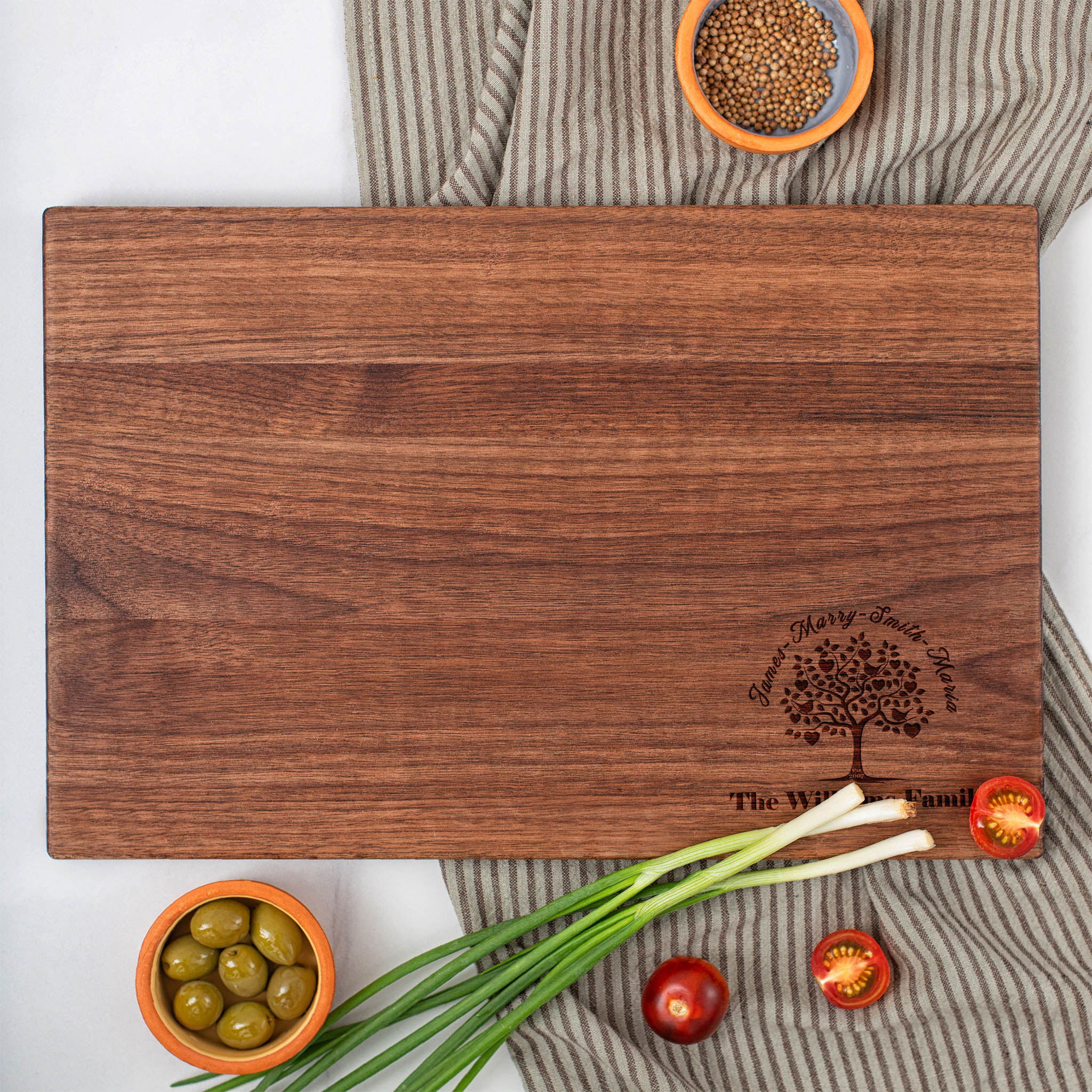 A walnut cutting board with olives and onions on it.