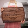 A woman is holding up a wooden cutting board.