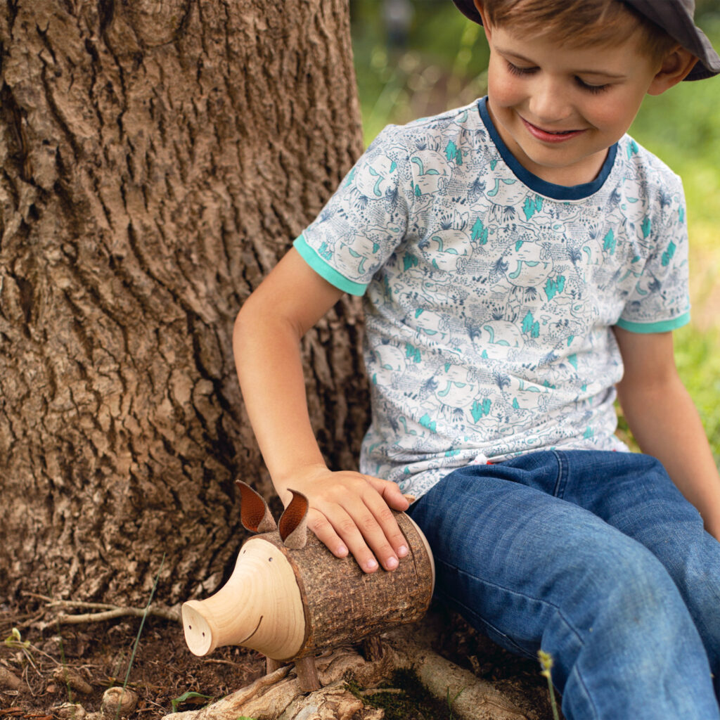 A young boy playing with a wooden pig.