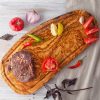 olive wood cheese board with a steak and vegetables on it.