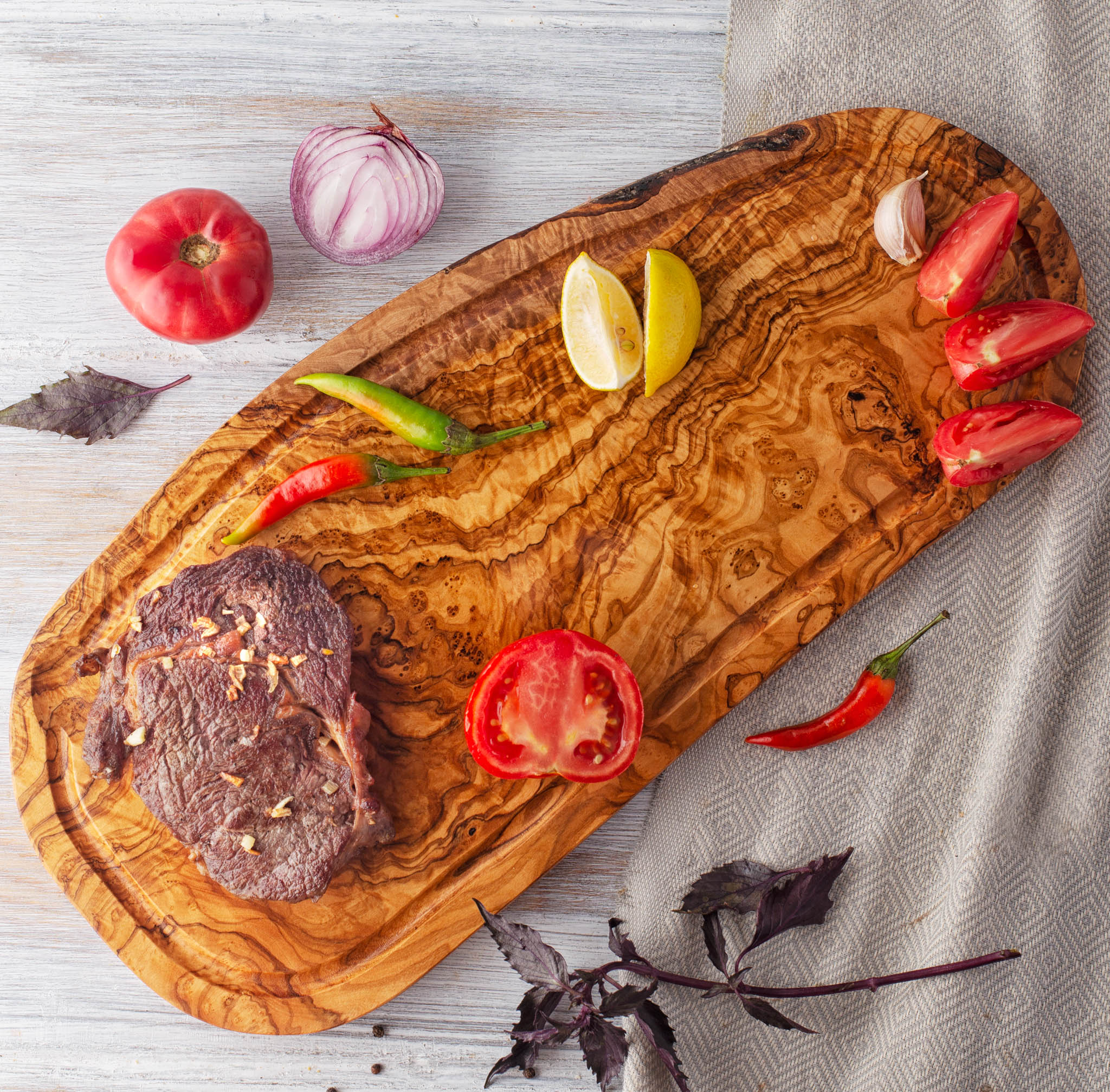 olive wood cheese board with a steak and vegetables on it.