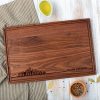 A walnut cutting board with a city skyline on it.