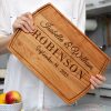 A woman is holding up a wooden cutting board.