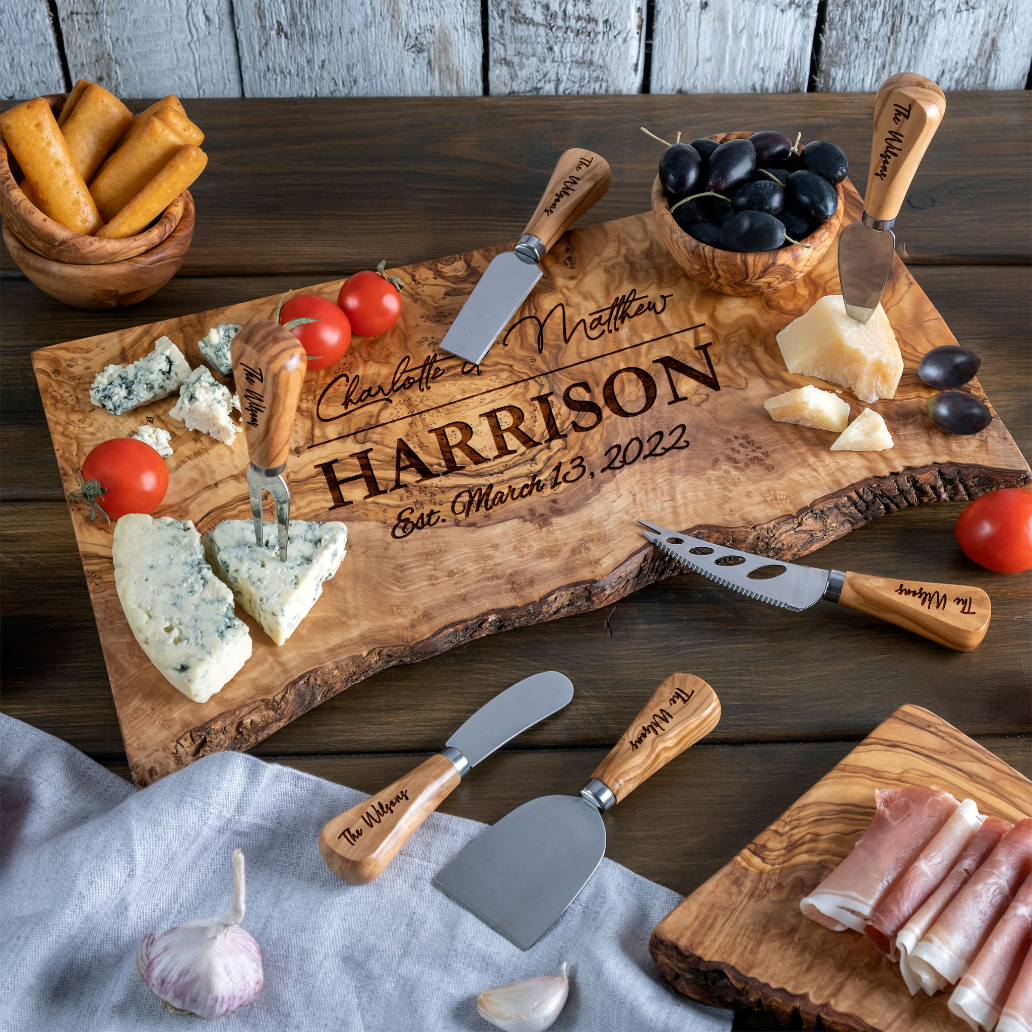A wooden cheese board with cheese, olives and meats on it.